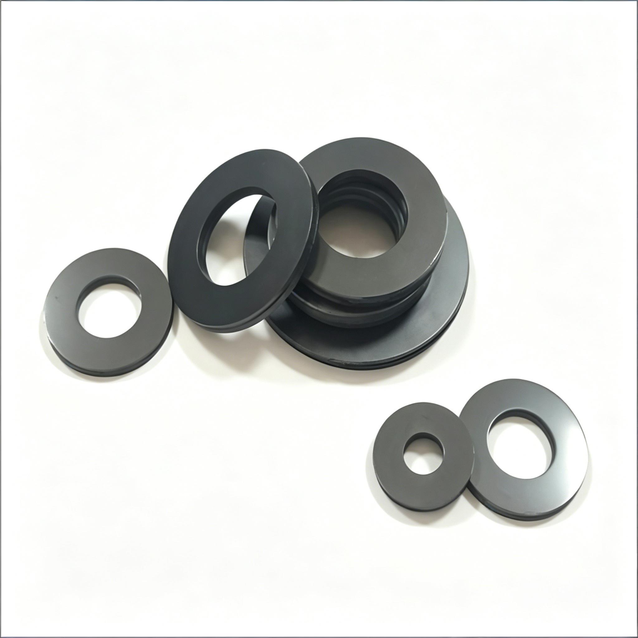 Assorted sizes of black graphite sealing rings and flat washers for industrial valve and pump applications.