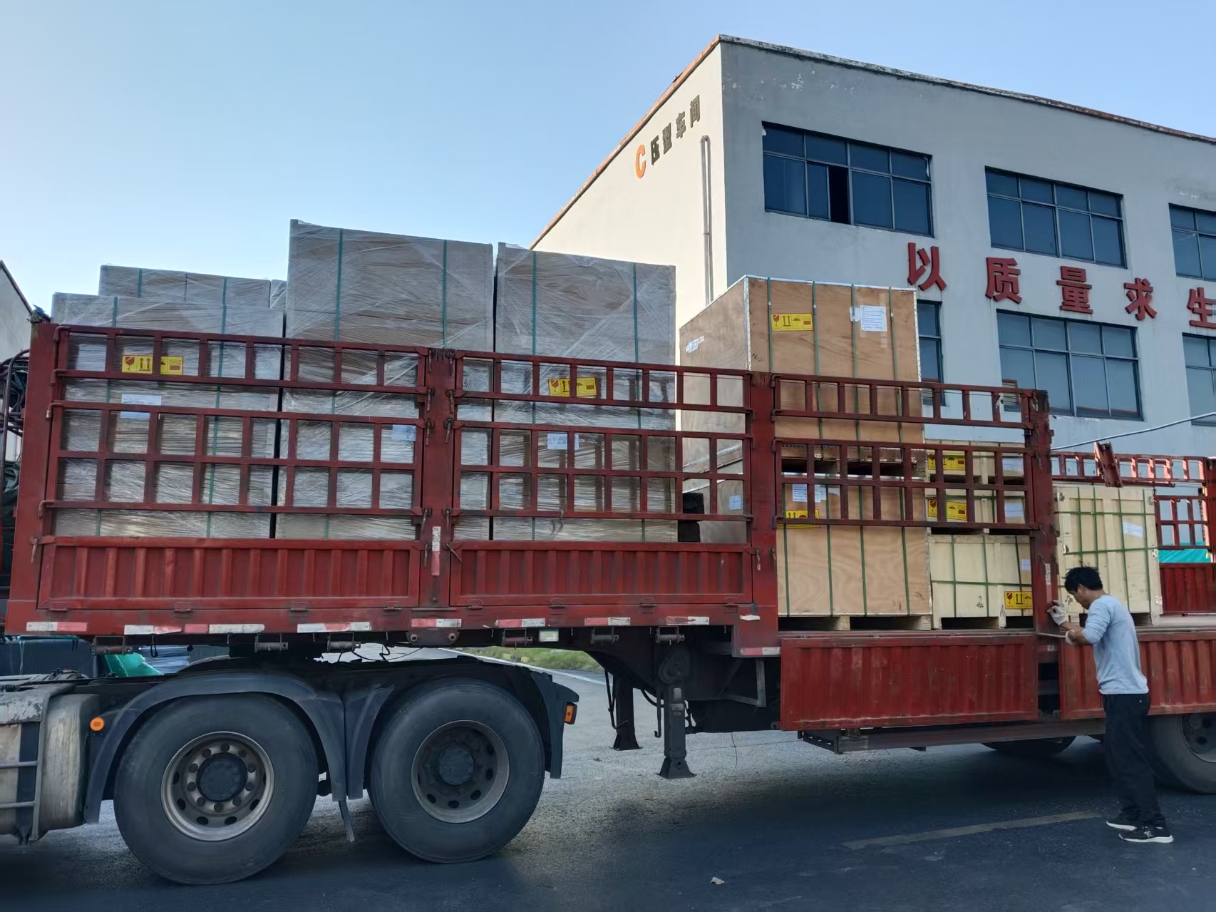 Workers securing large wooden packages of graphite heating elements onto a flatbed truck.