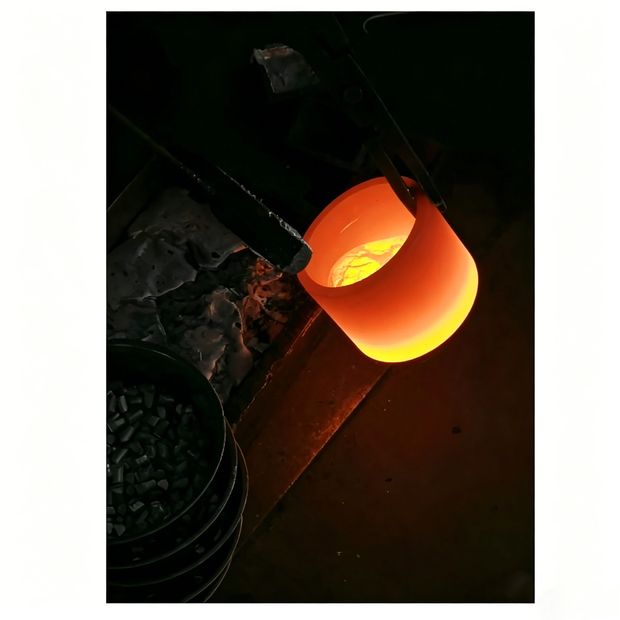 Glowing graphite crucible holding molten aluminum, used in vacuum evaporation coating process, demonstrating excellent thermal stability and corrosion resistance